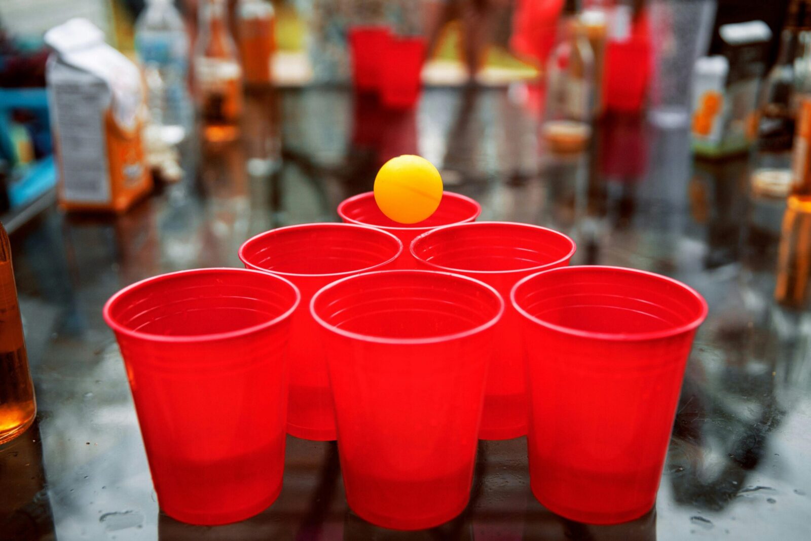 Close-up of red cups and ping pong ball set up for beer pong game at a party.